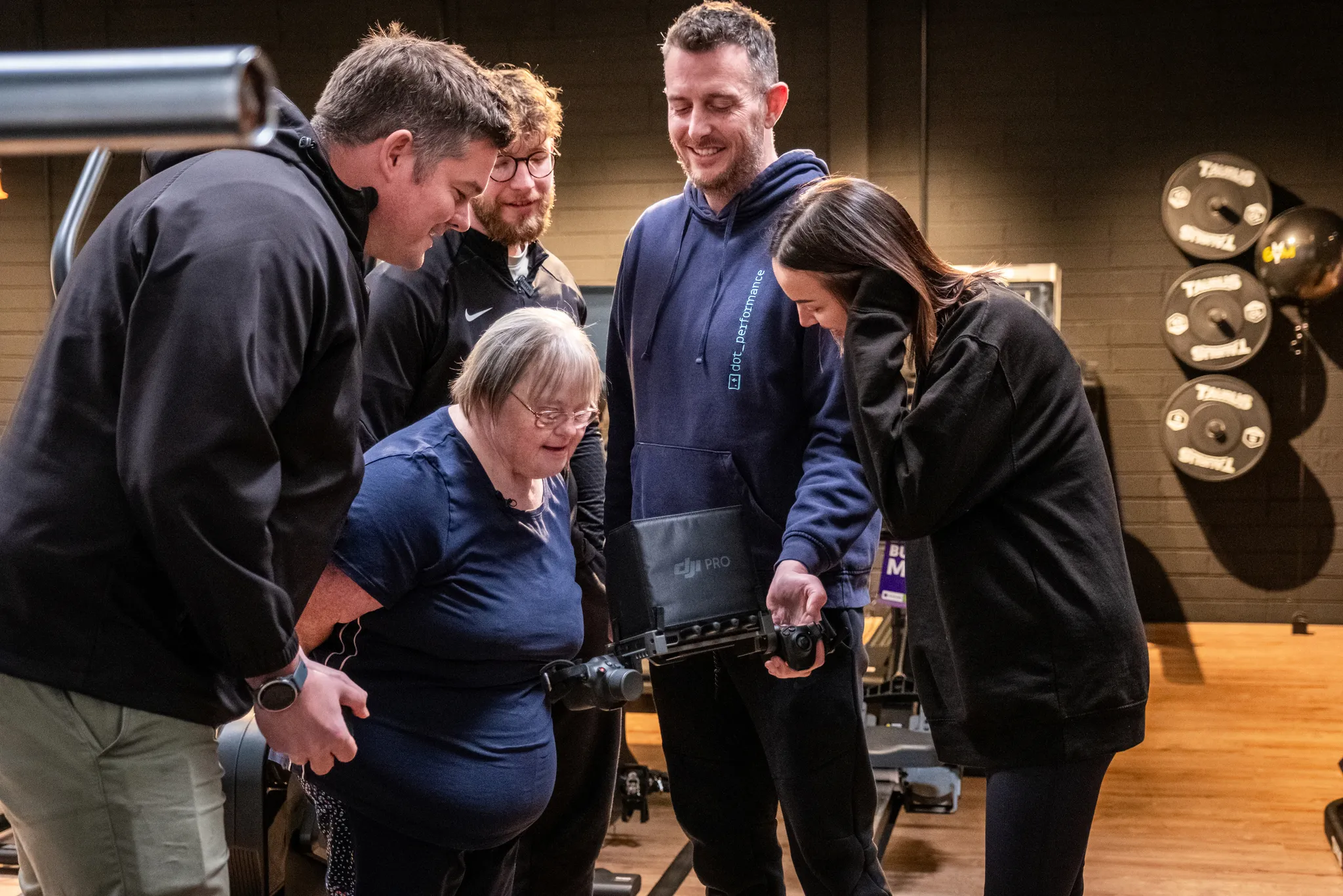 Julie Naylor, Danny Kane, Ian Drake, Katie Drake and Andy Orton reviewing footage on a DJI High Bright monitor at MyGym, Isle of Man, during production of the World Down Syndrome Day film